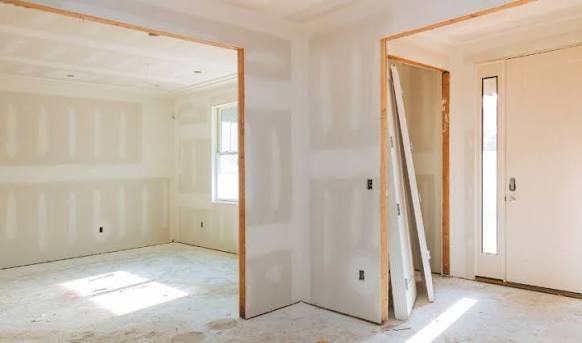 Interior rooms with freshly finished drywall around a doorway and entry
