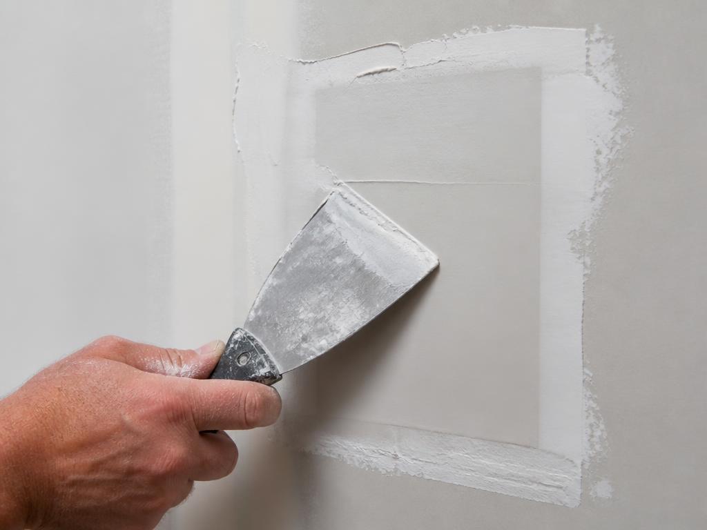 Drywall repair patch being carefully finished with joint compound